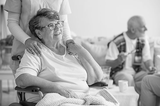 Aged care worker holding the shoulders of an elderly woman in a wheelchair