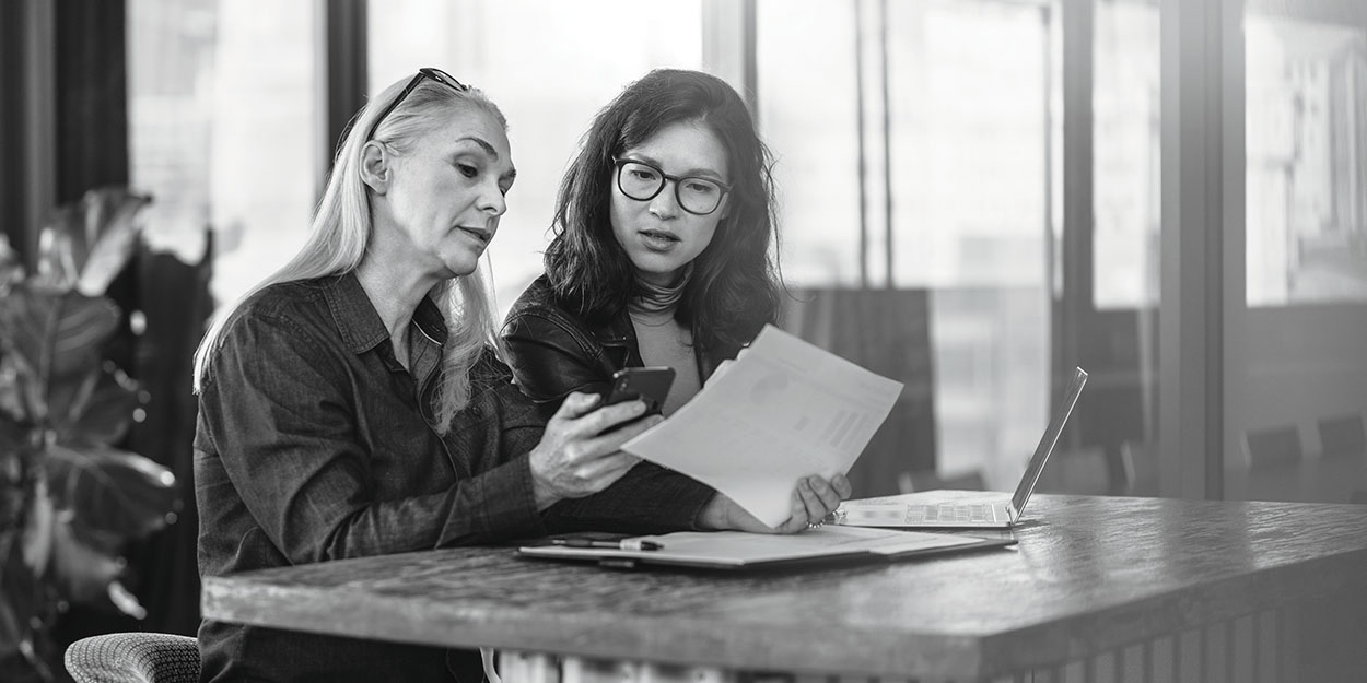 two business women having a casual meeting with laptop and paperwork
