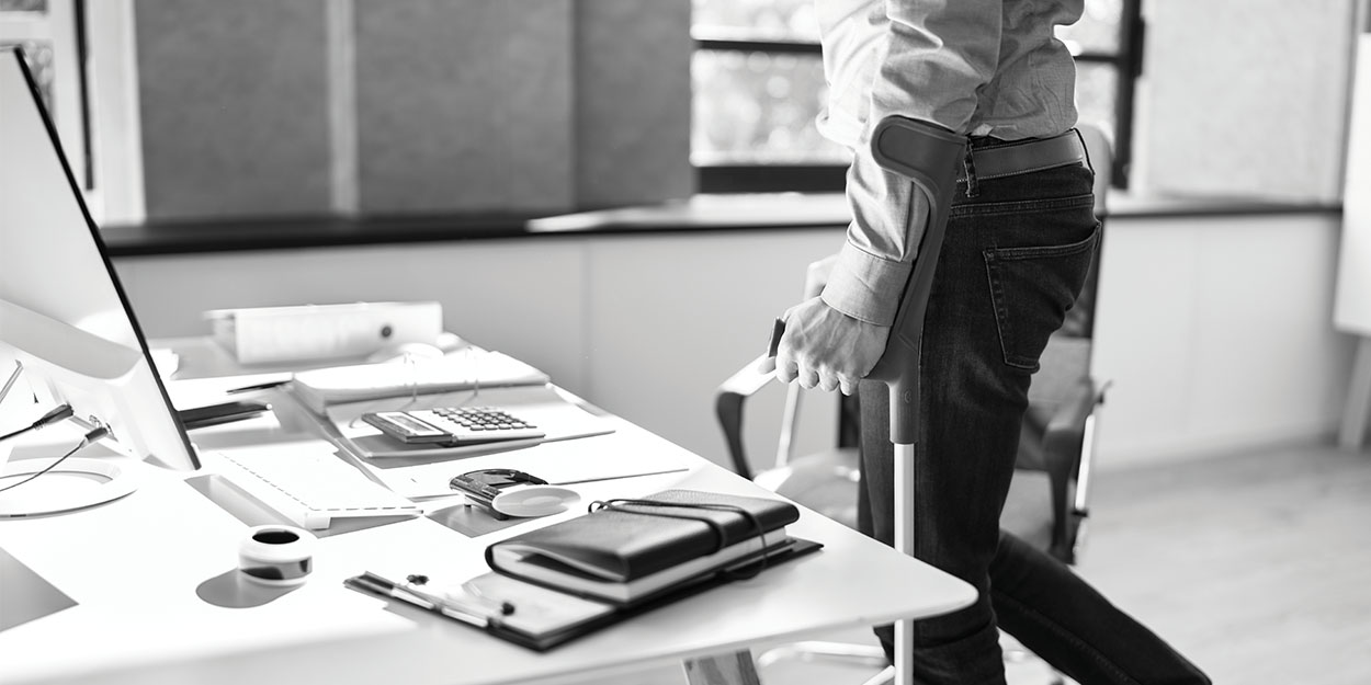 male holding crutches near a work desk